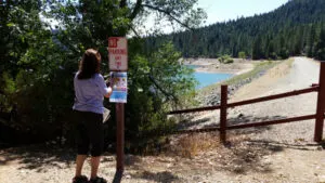 Volunteer posting state-issued fish consumption advisory sign at Scotts Flat Reservoir on July 11, 2015